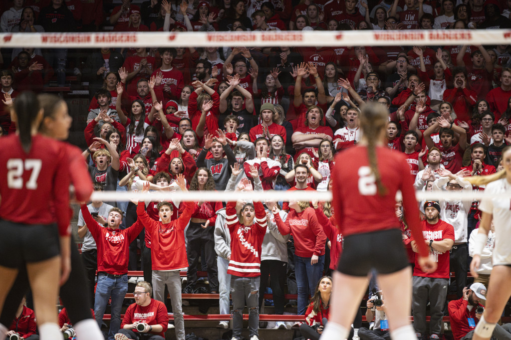 Red-clad fans cheer volleyball players.