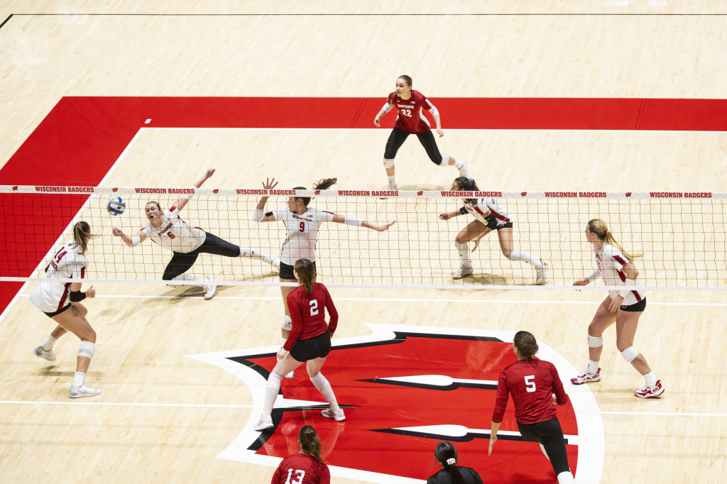 Players are spread out on the court, one dives for the ball.