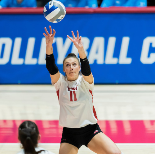 A woman in a volleyball uniform hits a ball.