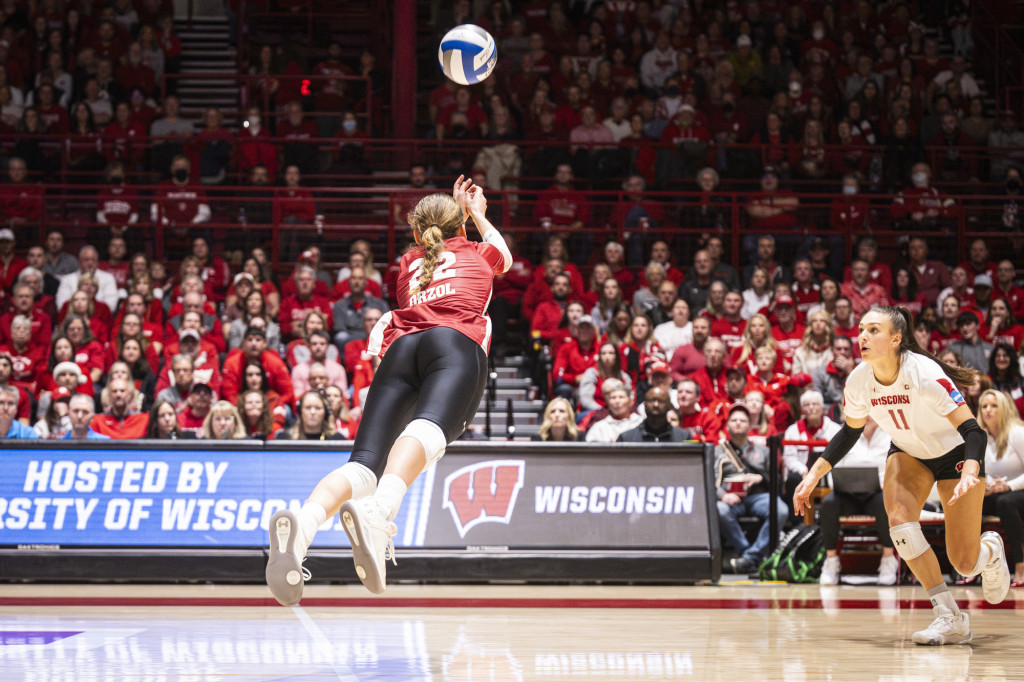 A woman in a volleyball uniform dives for a ball.