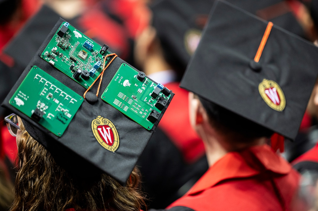 A person wears a mortarboard with computer circuitboards on it.