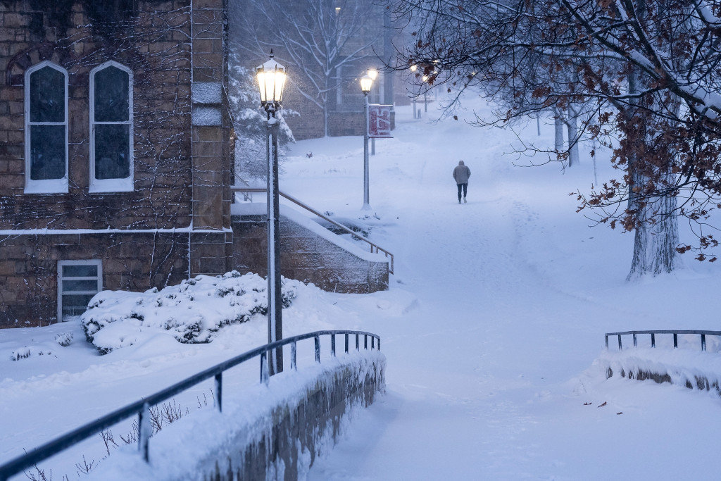Lamppost lights glow at dusk as a lone pedestrian walks up Bascom Hill on Jan. 12. At left is Music Hall. 
