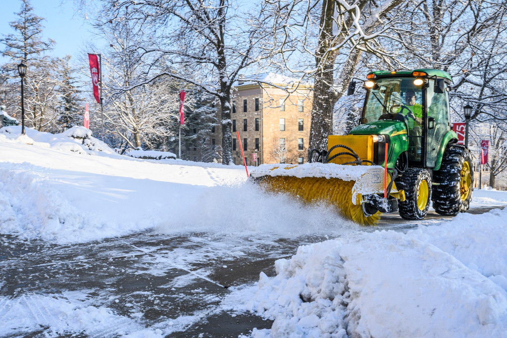 A snow clearing tractor does its work on a snowy sidewalk on Bascom Hill.