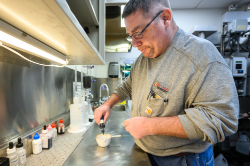A man works with laboratory equipment on a countertop.