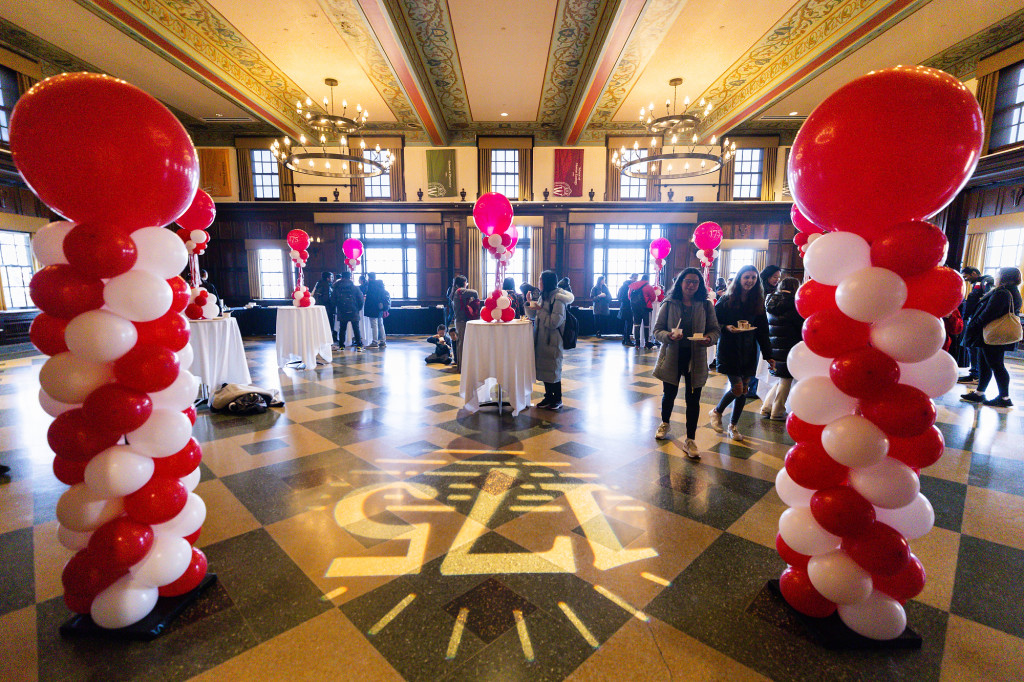A large room is decorated with red balloons and white tableclothes.