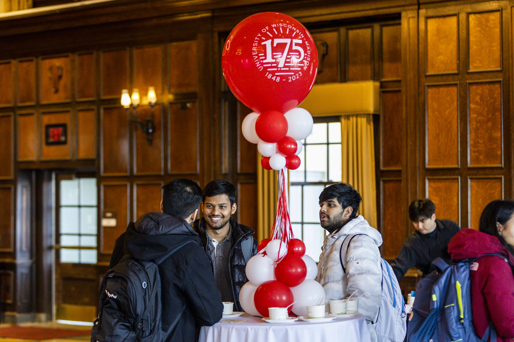 Two people stand at a table with a red balloon with 