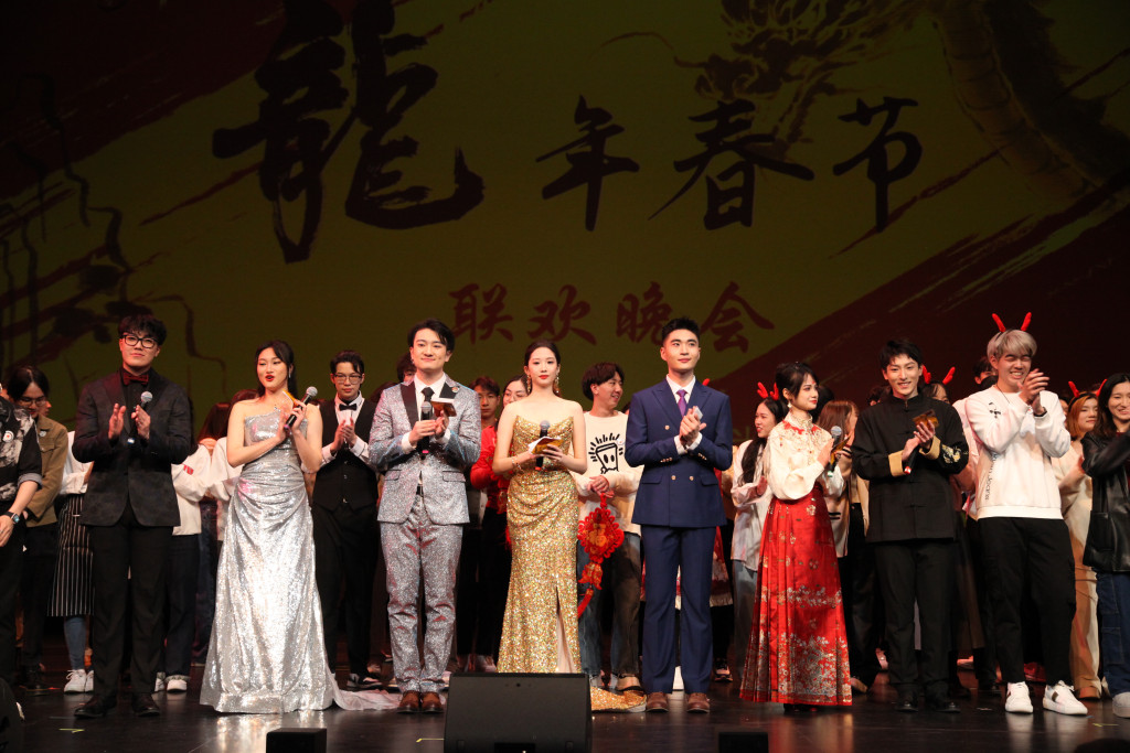 The hosts, organizers and performers for the Spring Festival Gala fill the stage and clap their hands in applause.