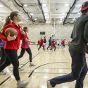 College students walk with purpose across the basketball court in the Bakke Center.