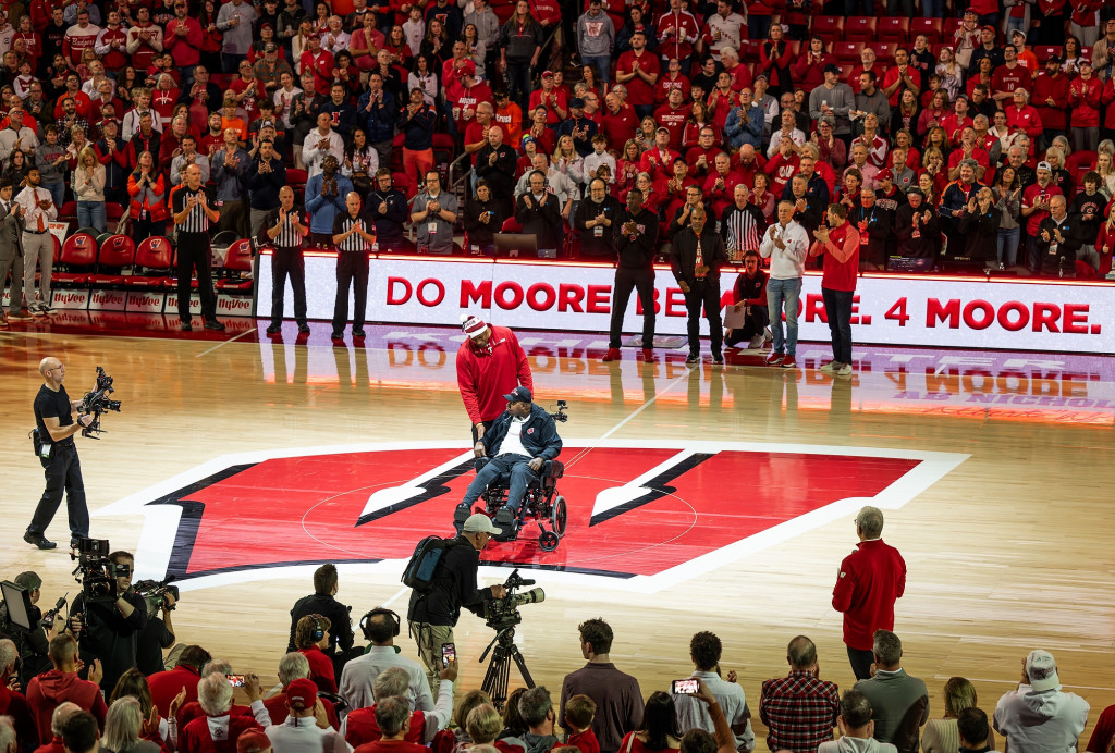 A man in a wheelchair is at center court, acknowledging applause.