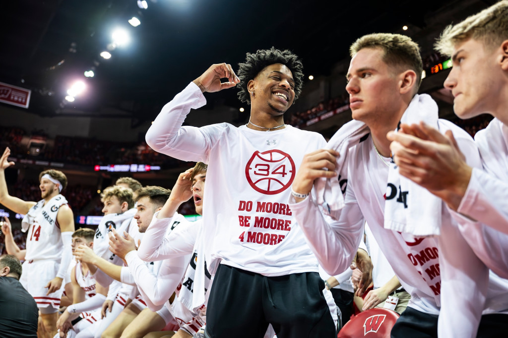 Players wear white warm-up shirts with red lettering on the sidelines.