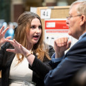 A woman gesticulates as she talks to a man.