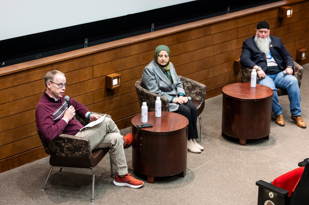 In a photo taken from above, John Zumbrunnen, Bibi Bahrami and Richard McKinney sit in chairs in front of a cinema screen as they participate in a panel discussion.
