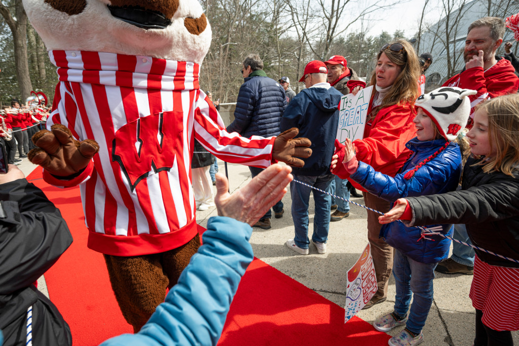 A person wearing a Bucky Badger outfit high-fives a child.