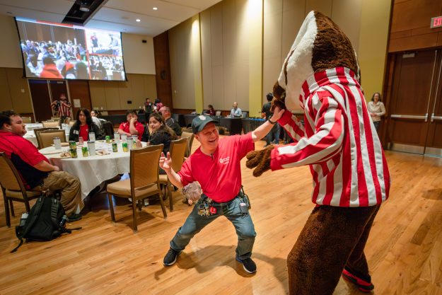 A man high-fives a person in a Bucky Badger costume.