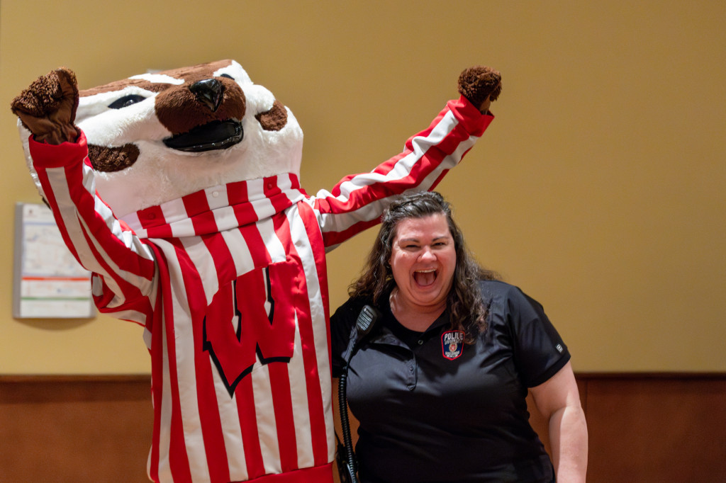 A person poses for a photo with Bucky Badger.