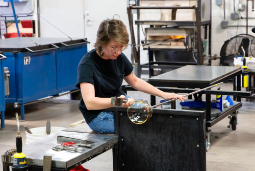 A photo of a woman blowing glass.