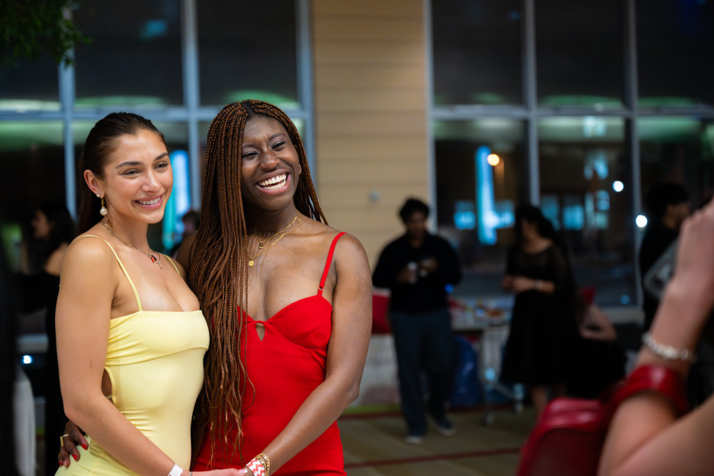 Two women in formal dresses smile and pose for a photo.