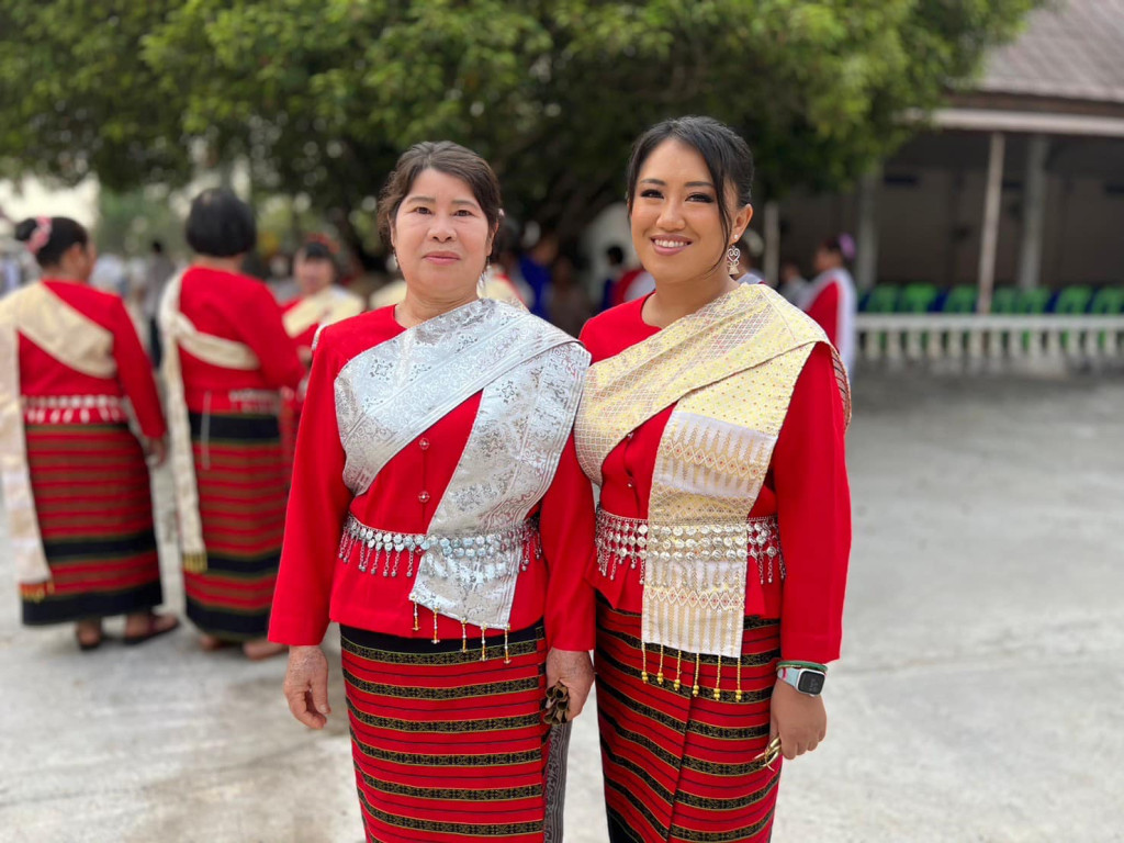 Two women in traditional dress smile for the camera.