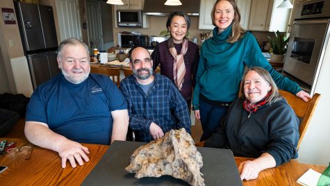 Farmers Jim Koch (far left) and Jan Shepel (far right) pose for a photo with a 110-pound found iron meteorite sitting on their family dining table at their home and Vienna EqHo Farm in the Town of Vienna, Wis., on March 21, 2024. Included in the photo are UW Geology Museum Director Rich Slaughter (second from left), Noriko Kita (center), a distinguished scientist and meteorite expert from UW–Madison, and Carrie Eaton (second from right), curator of the UW Geology Museum. The meteorite was unearthed by Jim Koch in May 2009 as he was plowing one of his farm fields. After storing the meteorite for some time, Koch and Shepel are now sharing their find with the public after agreeing to sell the Vienna Meteorite, as it's provisionally called, to the University of Wisconsin Geology Museum at a price significantly below its market value. (Photo by Jeff Miller / UW–Madison)