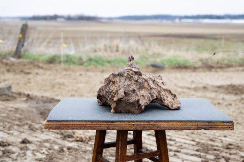A rock sits on a table in front of a field.