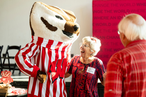 A woman smiles broadly as she leans in for a hug from Bucky Badger.