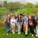 A group of people stand and pose for the camera in a green field.