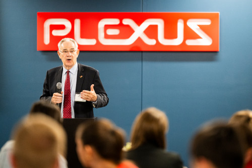 Ian Robertson stands before a seated crowd at the Plexus Neenah Operations Center. He is holding a microphone as he speaks.