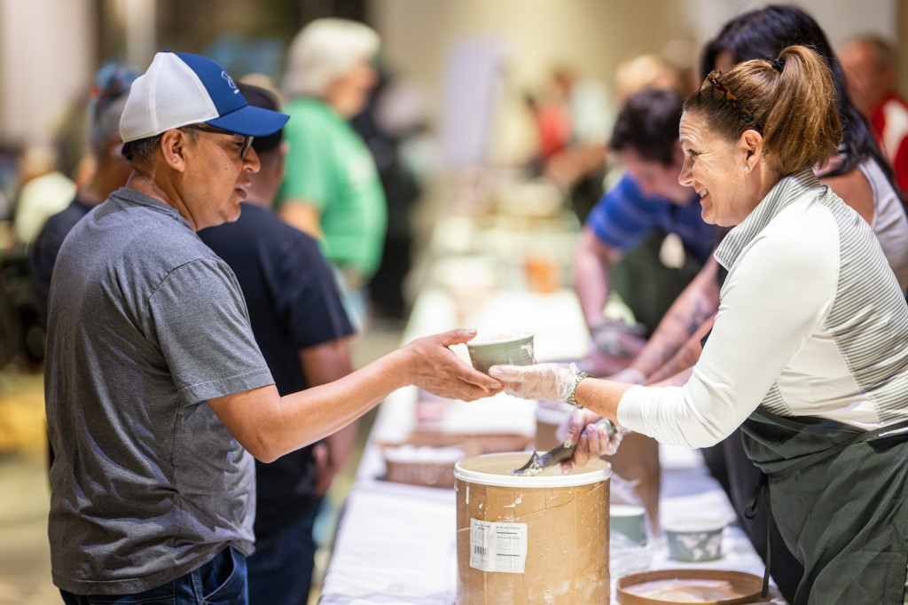 A woman hands ice cream to someone over a table.