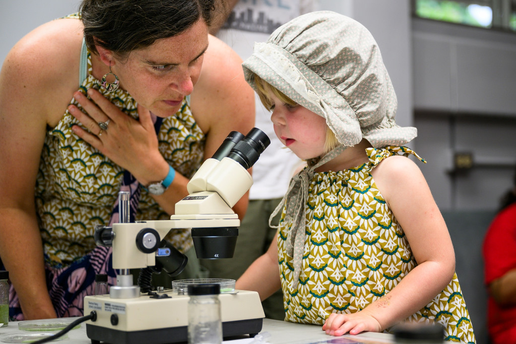 Anna Rusk and her almost-four-year-old daughter Eliza Rusk use a microscope to look for “little things in the water.” The family came for the boat rides, which were canceled due to stormy weather, but found lots of other activities at the open house instead. 