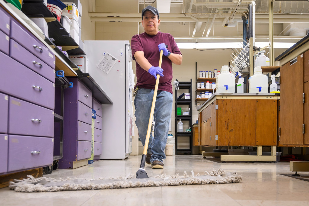 A man pushes a wide broom.