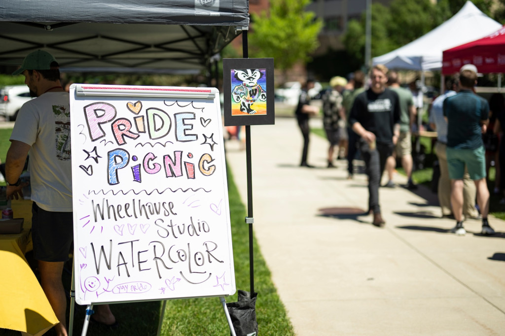 A sign advertises the Pride Picnic as people walk in the background.