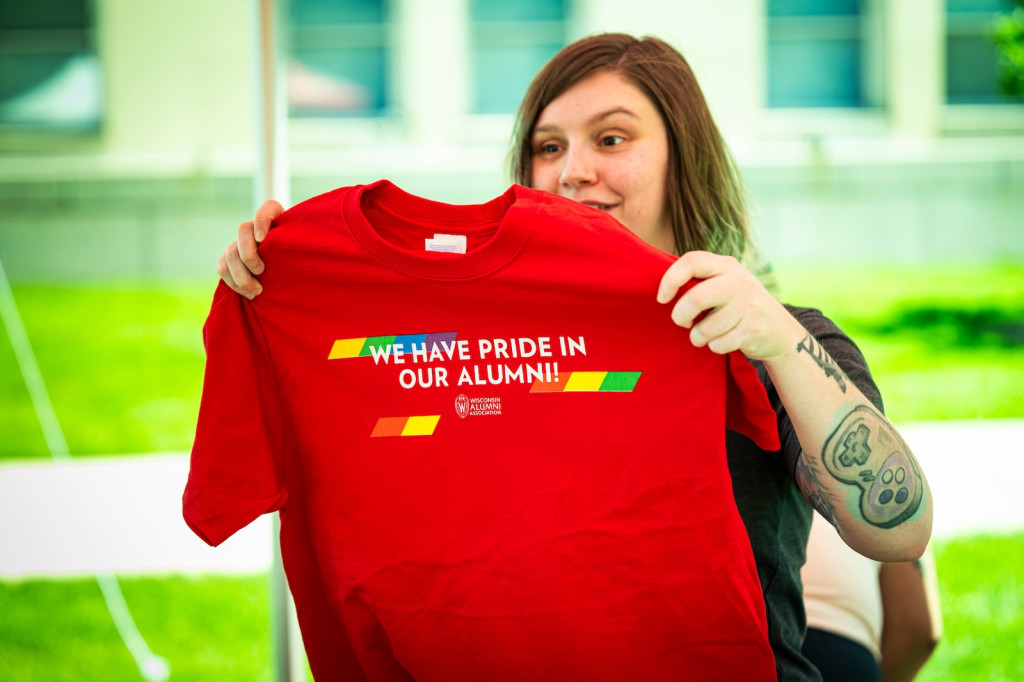 A woman hands out a red Pride t-shirt.