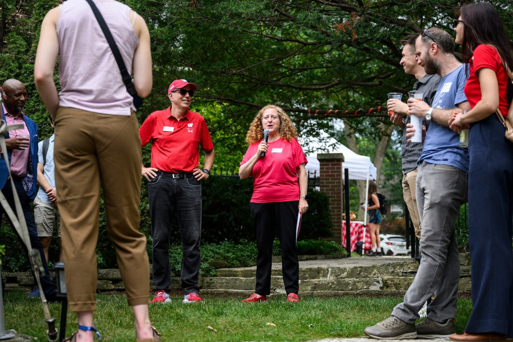 Two people in red shirts address an audience.