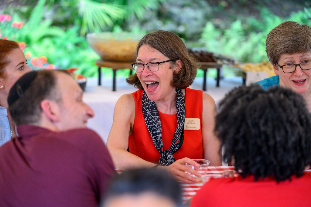 A woman sitting at a table smiles and laughs.