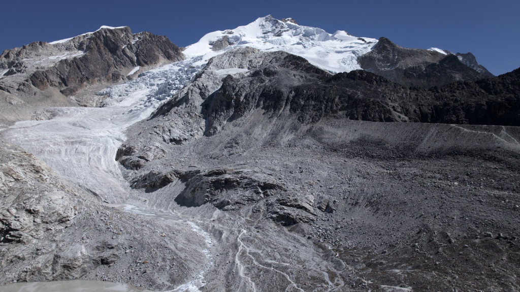 A photo of several snowy mountains, including a glacier.