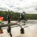 A person in scuba gear steps off the side of a boat into a Northwoods lake. A second person in the boat gets ready to follow him into the water.