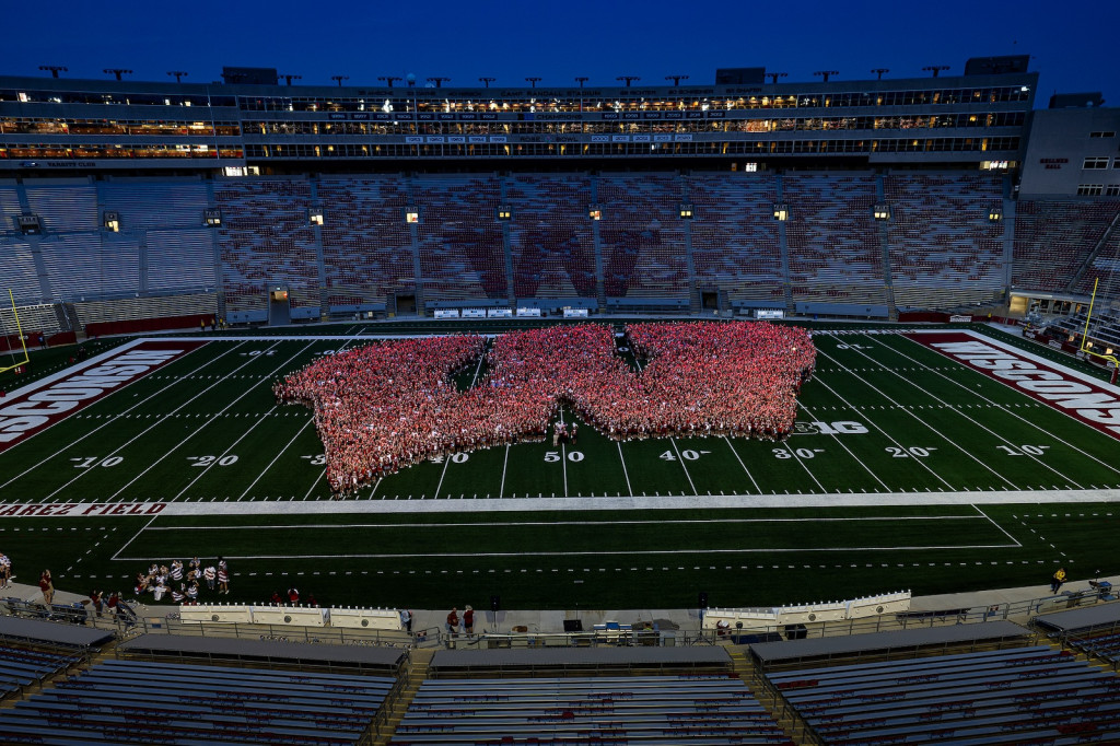 A stadium is shown at dusk, with students forming a W on the field.