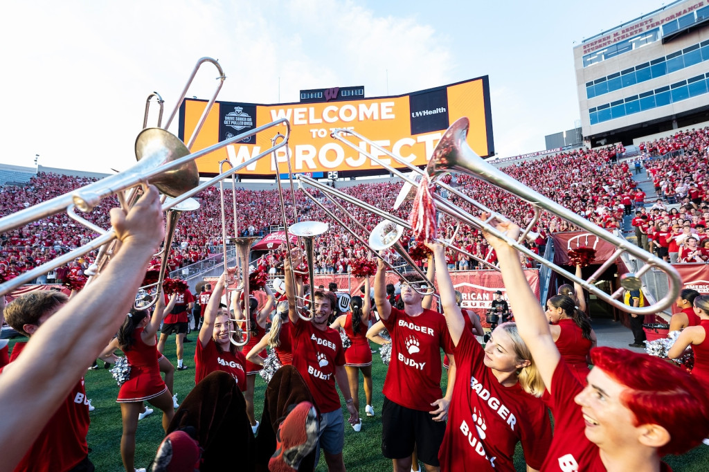 Horn players hold up their instruments in a circle as they lead cheers.