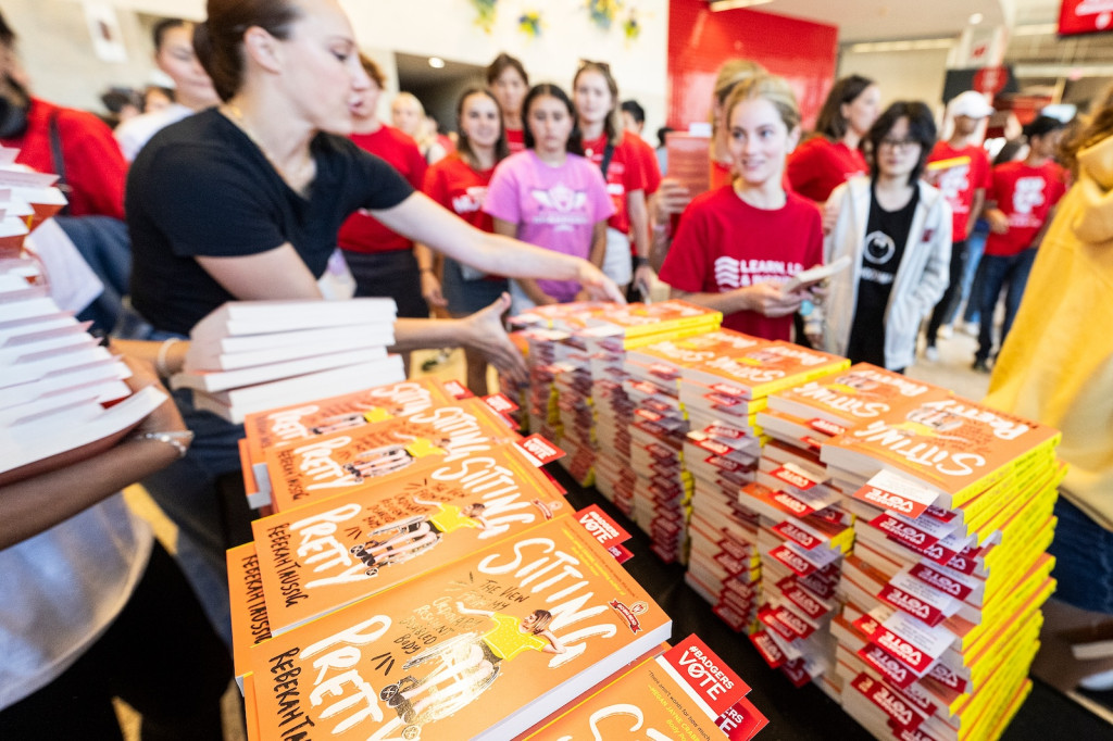 Students walk by a bunch of books and grab some.