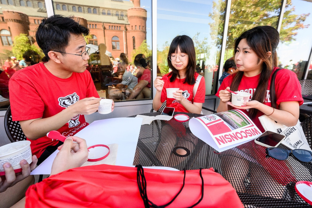 Students sit around a table and eat ice cream.