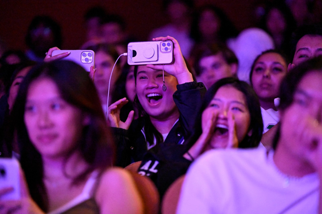 Smiling, laughing people in a crowd enjoy a performance in an auditorium.