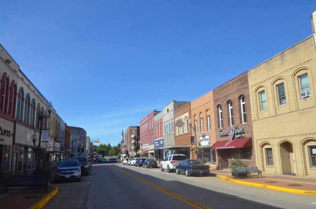 A city's downtown, with a row of businesses on a street, is shown.