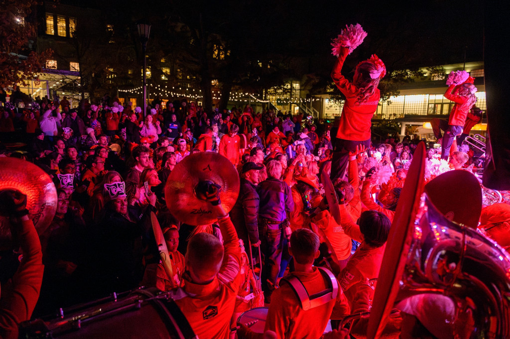 People bathed in red light play instruments and cheer excitedly.