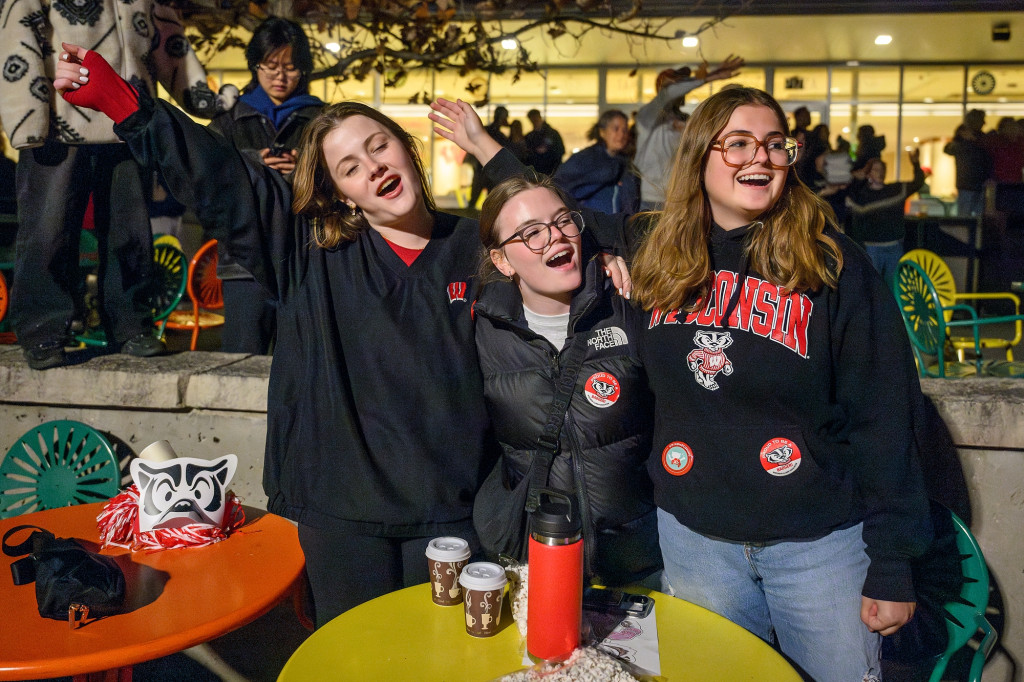 Three young women stand, smile and sing.