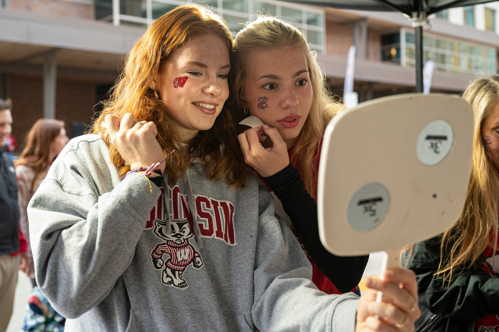 Two women look at their new temporary tattoos in a mirror.