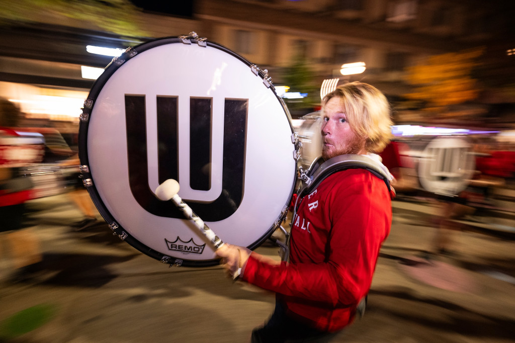 A man plays the bass drum as he marches in a parade.