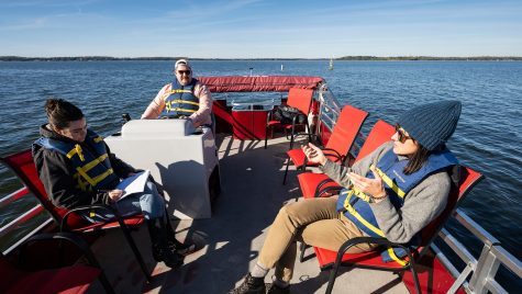 Several people sit in a pontoon boat.