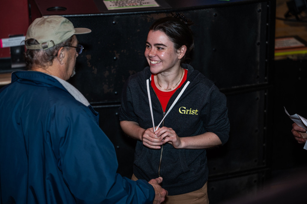 A woman is talking to another person, smiling and gesturing.