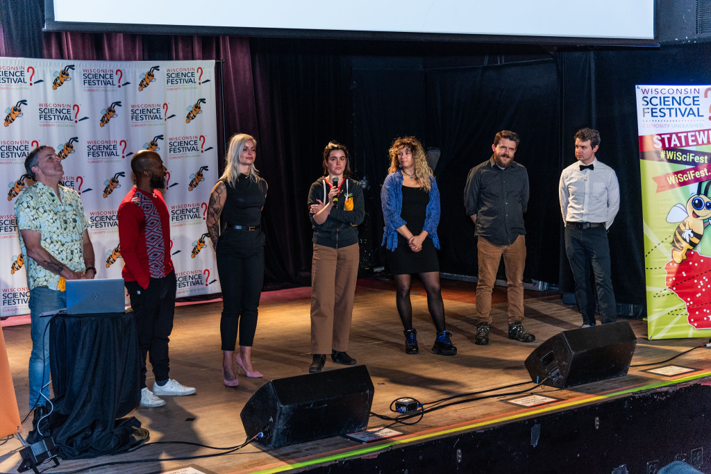 Several people stand on stage and talk.