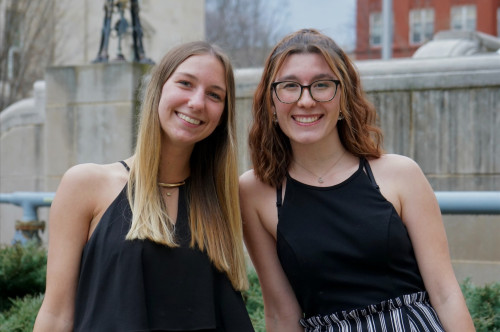 Two women sit closely together and smile for the camera.